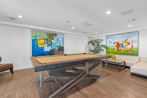 a pool table in a living room with paintings on the wall at The Social Apartments, North Hollywood, 91601